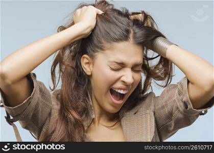 Close-up of a young woman screaming with her hands in her hair
