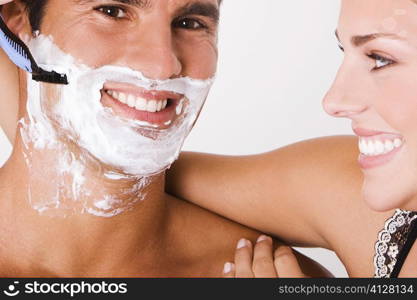 Close-up of a young woman shaving a mid adult man