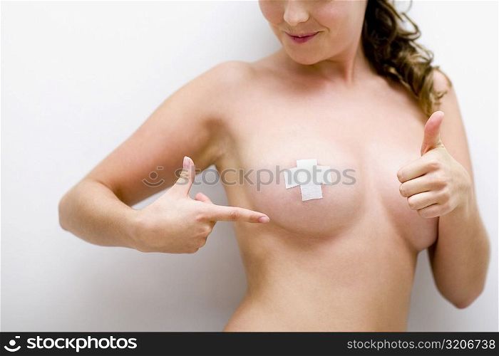 Close-up of a young woman showing adhesive bandage on her nipple