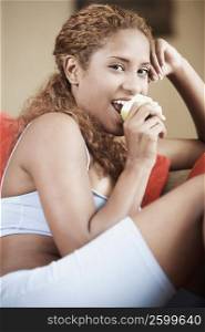 Close-up of a young woman sitting and eating an apple