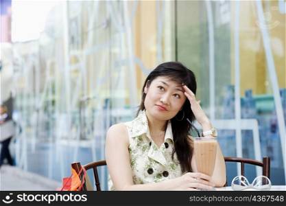 Close-up of a young woman sitting in a cafeteria with her hands on her head