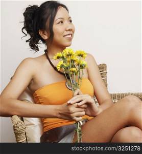 Close-up of a young woman sitting in an armchair and holding flowers