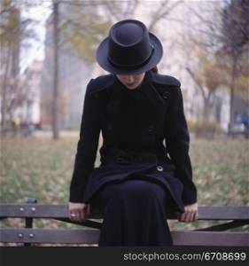 Close-up of a young woman sitting on a bench in a park