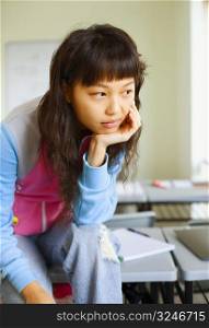 Close-up of a young woman sitting on desk and thinking in the classroom