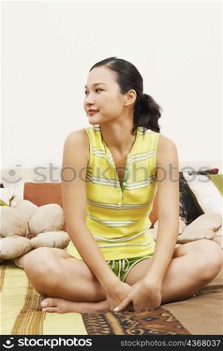 Close-up of a young woman sitting on the bed and thinking