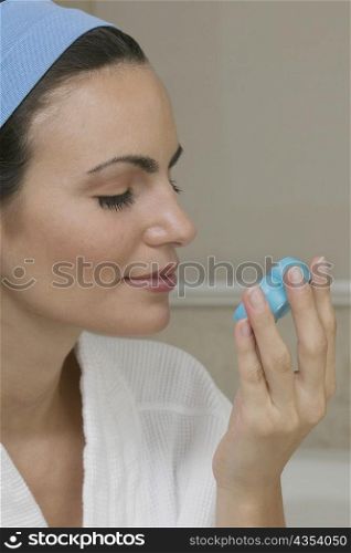 Close-up of a young woman smelling a bar of soap