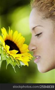 Close-up of a young woman smelling a sunflower
