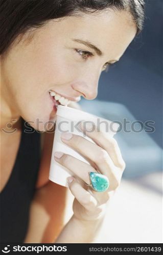 Close-up of a young woman smiling and drinking coffee