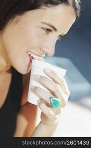 Close-up of a young woman smiling and drinking coffee