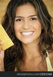 Close-up of a young woman smiling and holding a biscuit