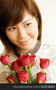 Close-up of a young woman smiling and holding a bouquet of red roses