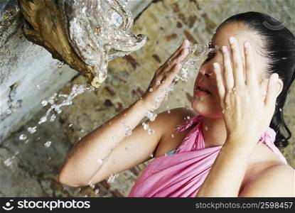 Close-up of a young woman splashing water on her face