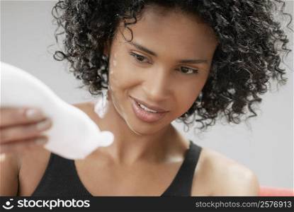 Close-up of a young woman squeezing a moisturizer bottle