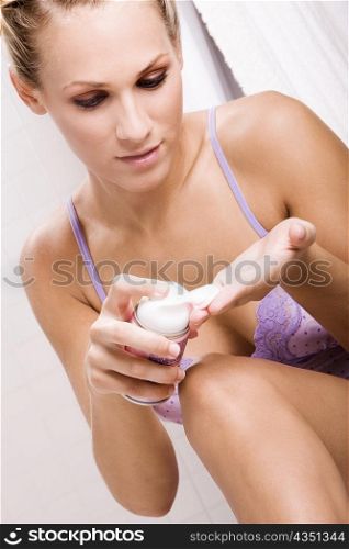 Close-up of a young woman squeezing shaving cream on her hand