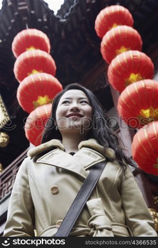 Close-up of a young woman standing in front of hanging Chinese lanterns