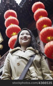 Close-up of a young woman standing in front of hanging Chinese lanterns