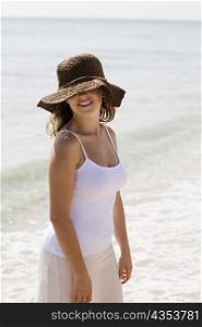 Close-up of a young woman standing on the beach and smiling