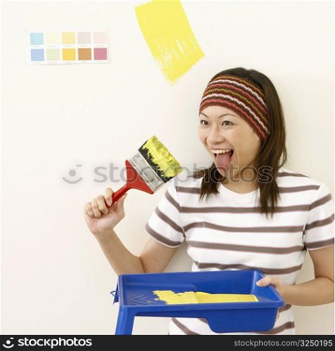 Close-up of a young woman sticking her tongue out and holding a paintbrush
