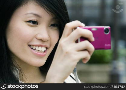 Close-up of a young woman taking a picture with a digital camera