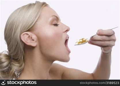Close-up of a young woman taking a spoon full of pills