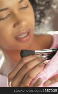 Close-up of a young woman taking make-up brushes from her purse