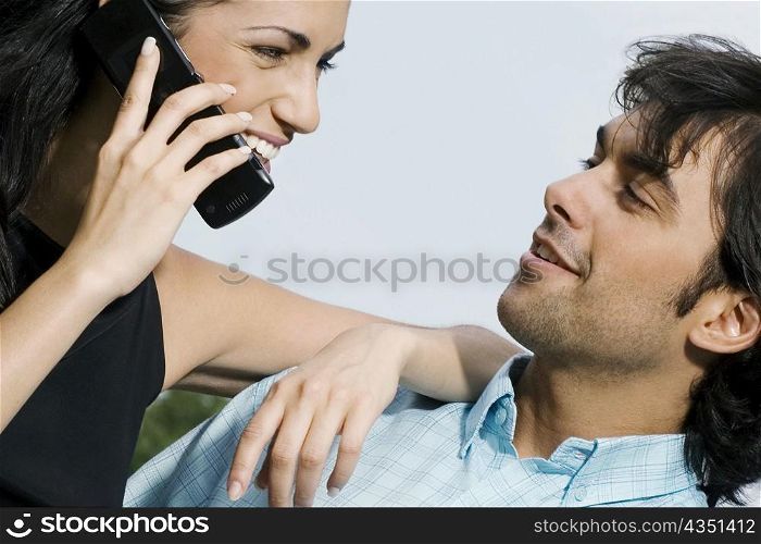 Close-up of a young woman talking on a mobile phone and looking at a young man