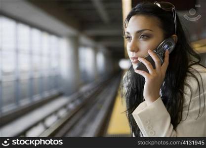 Close-up of a young woman talking on a mobile phone at a subway station