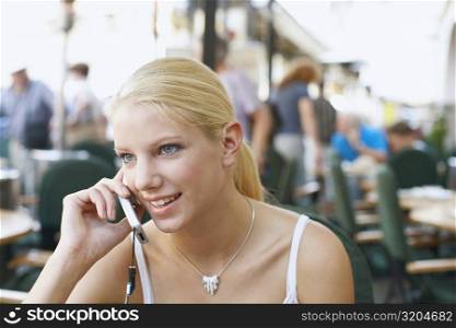 Close-up of a young woman talking on a mobile phone in a restaurant