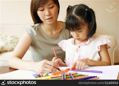Close-up of a young woman teaching her daughter to color