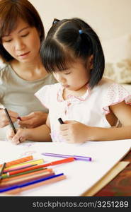 Close-up of a young woman teaching her daughter to color