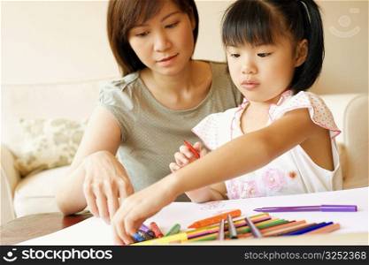 Close-up of a young woman teaching her daughter to color