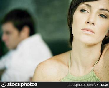 Close-up of a young woman thinking and a young man in the background