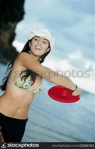 Close-up of a young woman throwing a plastic disc on the beach