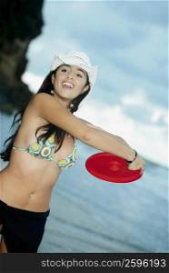 Close-up of a young woman throwing a plastic disc on the beach