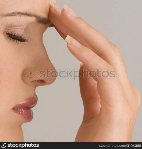 Close-up of a young woman touching her forehead