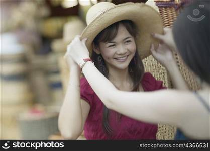 Close-up of a young woman trying on a straw hat