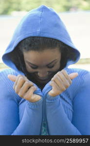 Close-up of a young woman trying to hide her face in her hooded shirt