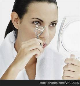 Close-up of a young woman using a eyelash curler