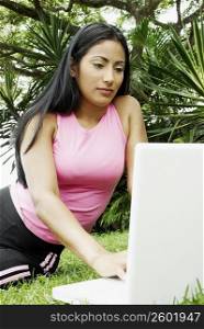 Close-up of a young woman using a laptop and sitting on the grass