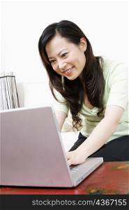 Close-up of a young woman using a laptop and smiling
