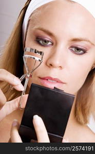 Close-up of a young woman using an eyelash curler