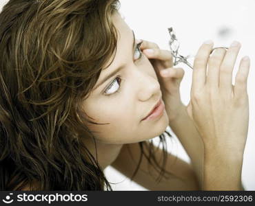 Close-up of a young woman using an eyelash curler