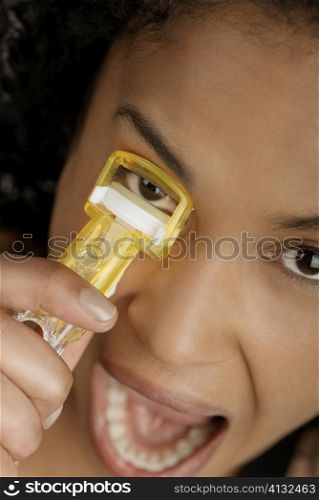 Close-up of a young woman using an eyelash curler