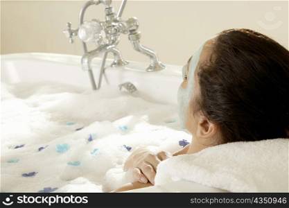 Close-up of a young woman wearing a facial mask in a bathtub