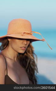 Close-up of a young woman wearing a hat on the beach