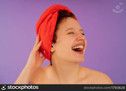 Close-up of a young woman wearing a towel on her head and smiling while standing against an isolated background. Beauty concept.