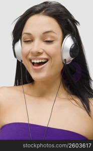 Close-up of a young woman wearing headphones and listening to music