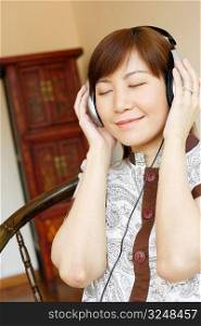 Close-up of a young woman wearing headphones and listening to music