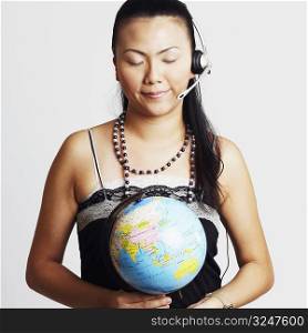 Close-up of a young woman wearing headset and holding a globe