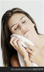Close-up of a young woman wiping her face with a towel